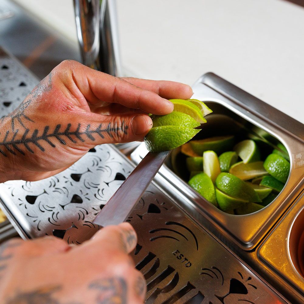 Hands cutting a lime at a cocktail bar