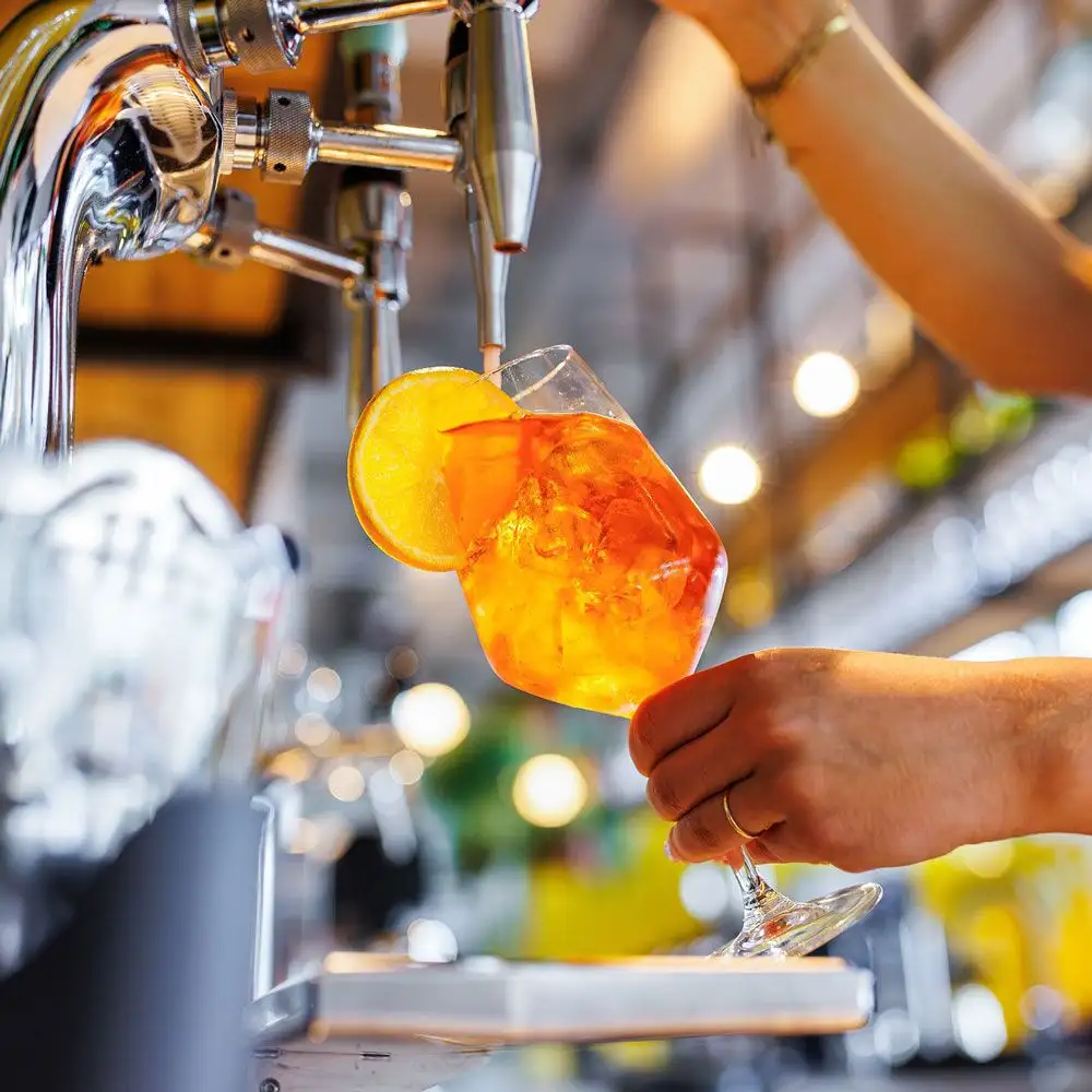 Bartender pouring an orange cocktail into a wine glass from a Springbay cocktail tap