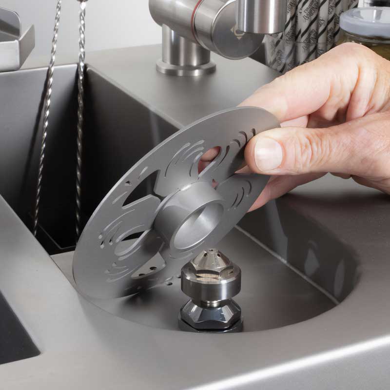 Bartender fitting the engraved stainless steel rinser lid into the station's sink