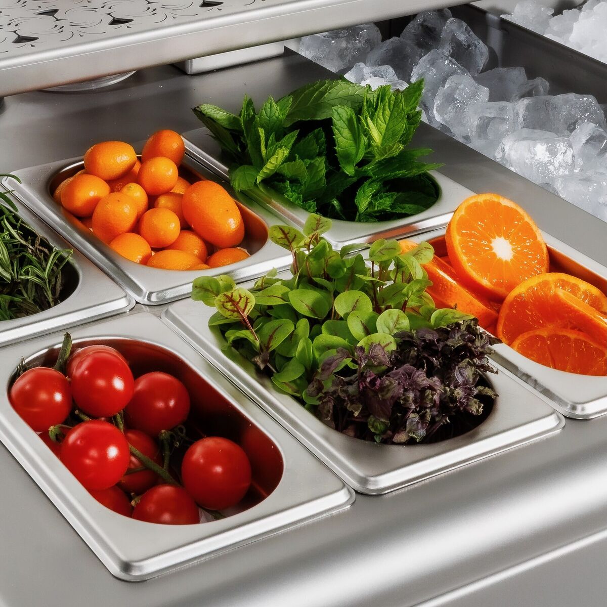 Garnish trays with tomatoes, mint, salad and orange next to crushed ice